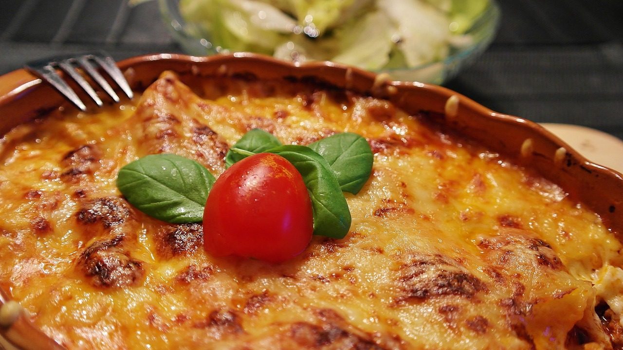 A baked pasta dish with melted cheese, basil and a tomato, ready to share